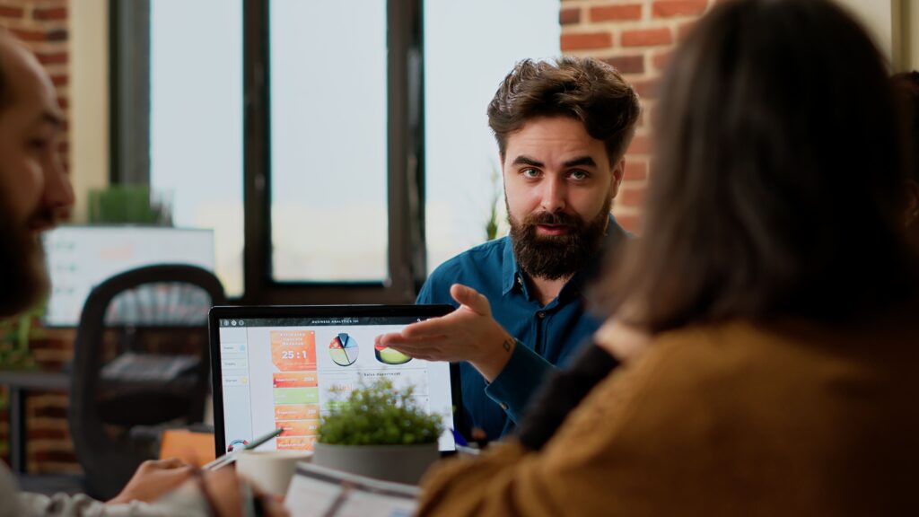 project manager pointing business charts laptop showing online research data colleagues people planning startup project presentation with charts creating successful report 2 1024x576